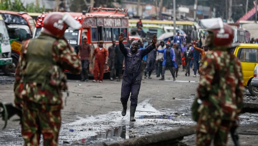 Un_manifestante_alza_le_mani_mentre_cammina_verso_la_polizia_antisommossa_durante_le_proteste_nella_capitale_Nairobi_in_Kenya.jpeg